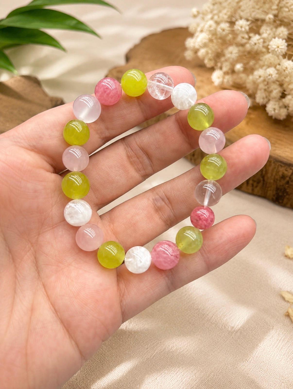 May include: A stretch bracelet composed of round, polished beads in a variety of colors including translucent white, pale pink, vibrant lime green, and deep rose pink. The beads are strung together in a circular pattern on an elastic cord.