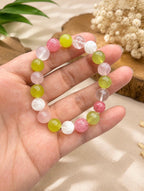 May include: A stretch bracelet composed of round, polished beads in a variety of colors including translucent white, pale pink, vibrant lime green, and deep rose pink. The beads are strung together in a circular pattern on an elastic cord.