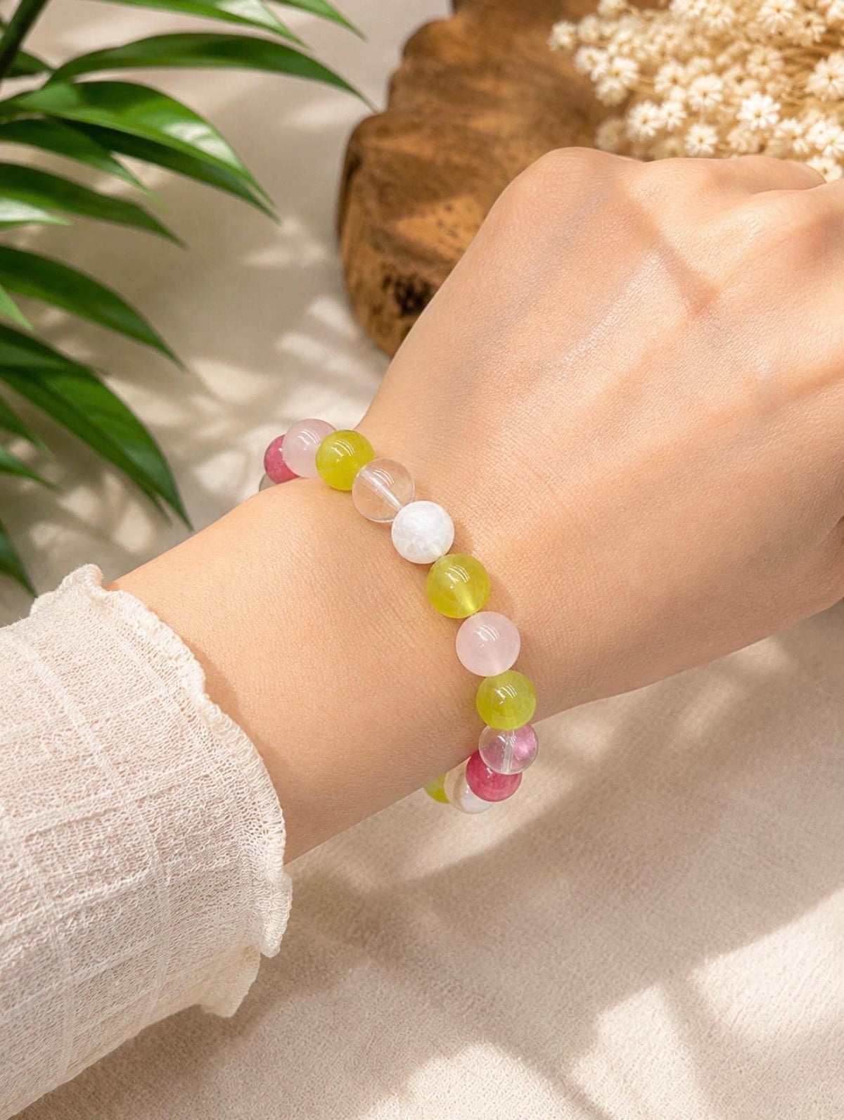 May include: A beaded bracelet featuring a sequence of smooth, round gemstone beads in translucent pink, vibrant lime green, clear white, and opaque white. The beads are strung together on an elastic cord, creating a colorful and polished accessory.